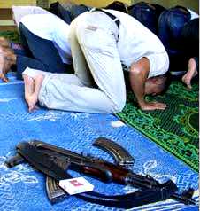 un musulman se prosterne dans une mosque, son fusil  porte de main